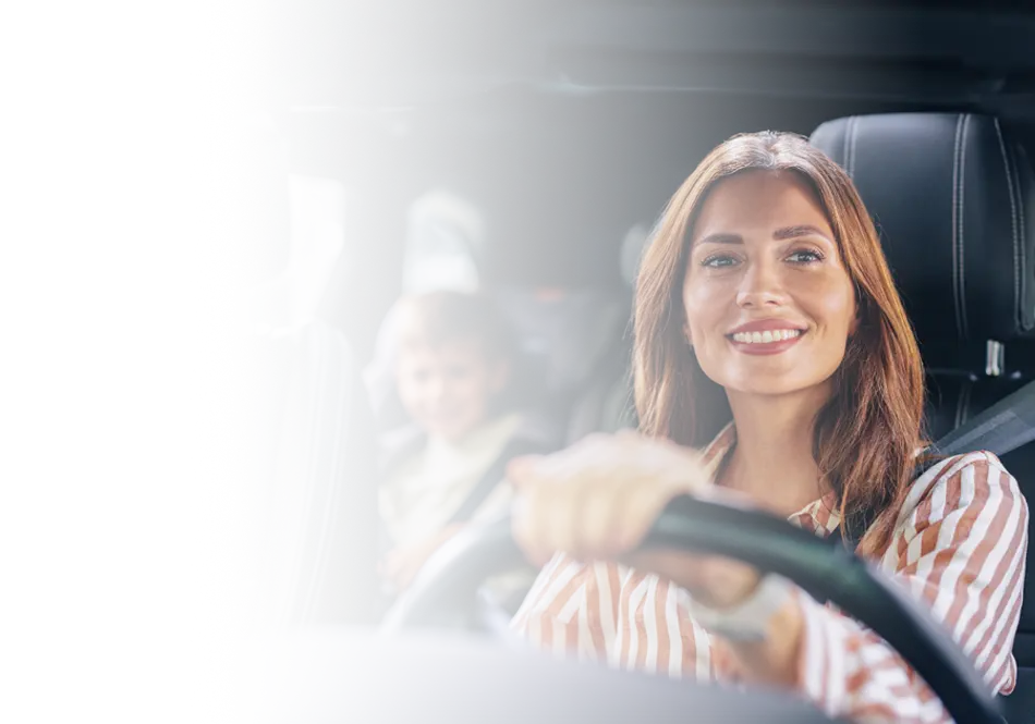 A smiling woman driving, eflecting auto insurance themes of safe travel and protection on the road.